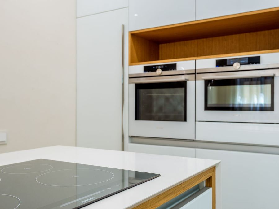 Hornos y placa de cocina empotrados, nuevos, en una cocina blanca.